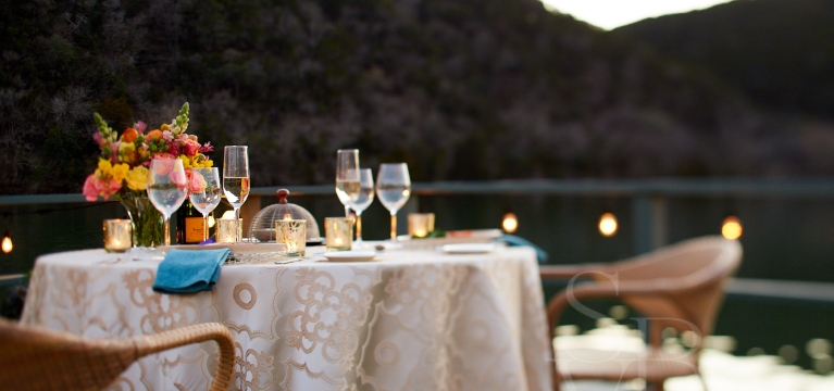 Table set up with champagne glasses and flowers in the evening looking out to the lake