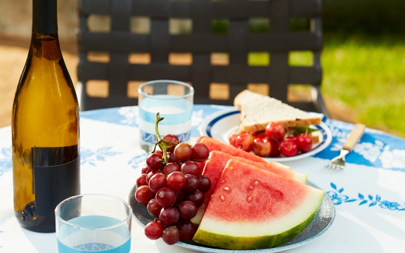 Outdoor table set with wine, sandwiches and fresh fruit