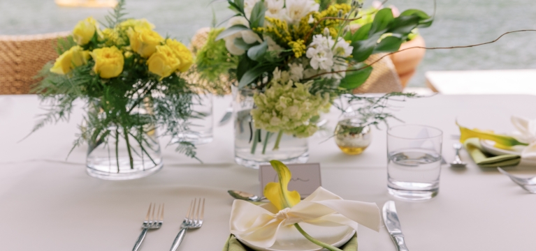 A beautifully arranged vase next to a set of plates and forks