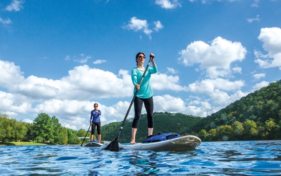 A man and woman use stand-up paddleboards on a sunny day.